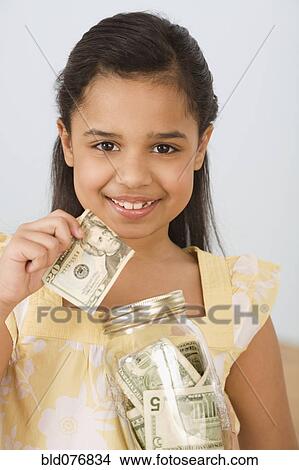 Picture - Hispanic girl holding money and jar. Fotosearch
