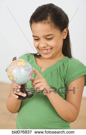 Stock Photo - Hispanic girl pointing at small globe. Fotosearch
