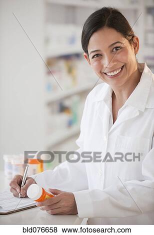 Stock Photo - Hispanic pharmacist holding prescription bottle. Fotosearch