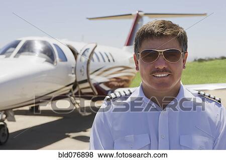 Hispanic pilot standing outside private jet View Large Photo Image Stock Photo - Hispanic pilot standing outside private jet. Fotosearch