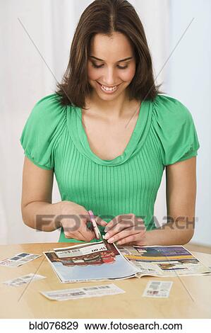 Stock Photo - Hispanic woman clipping coupons. Fotosearch