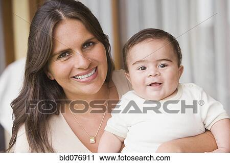 Stock Image - Hispanic woman holding baby boy. Fotosearch