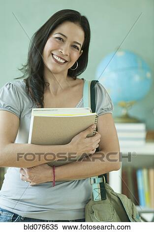 Hispanic woman holding books in classroom View Large Photo Image Stock Photography - Hispanic woman holding books in classroom. Fotosearch