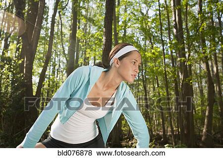 Stock Photo - Hispanic woman stretching in forest. Fotosearch