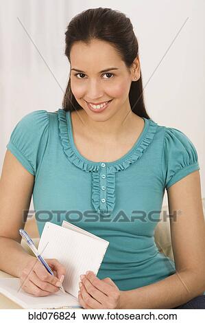 Picture - Hispanic woman writing in journal. Fotosearch