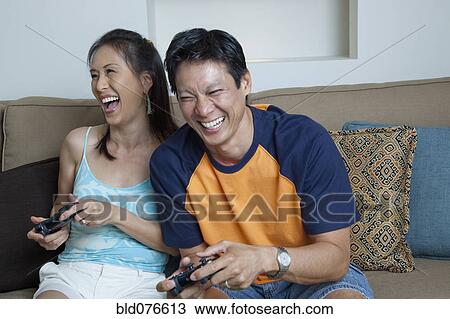 Japanese couple playing video games in living room View Large Photo Image Stock Image - Japanese couple playing video games in living room. Fotosearch