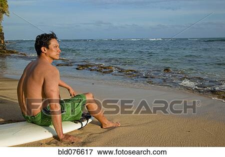Japanese man sitting on surfboard on beach View Large Photo Image Stock Photo - Japanese man sitting on surfboard on beach. Fotosearch