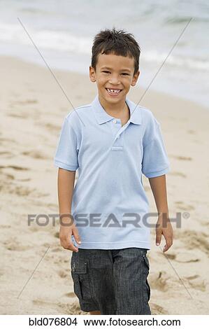 Picture - Mixed race boy walking on beach. Fotosearch