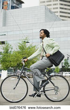Mixed race businessman riding bicycle in city View Large Photo Image Stock Photograph - Mixed race businessman riding bicycle in city. Fotosearch