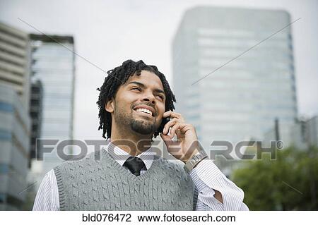 Stock Image - Mixed race businessman using cell phone in city. Fotosearch