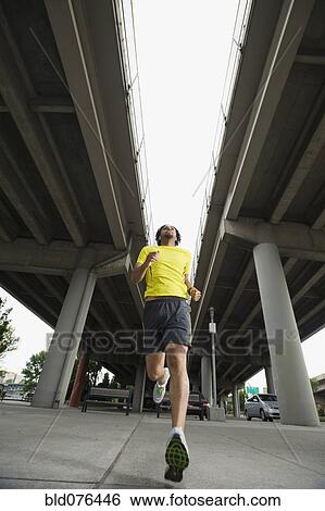 Stock Photograph - Mixed race man running under freeway overpass. Fotosearch