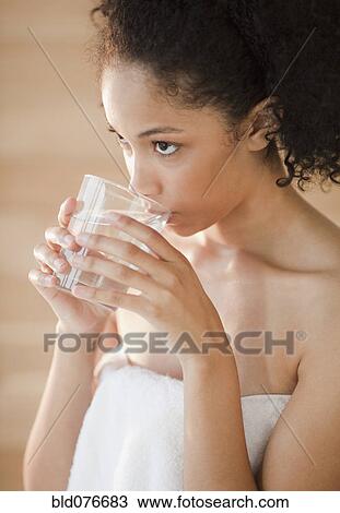 Stock Image - Mixed race woman drinking water. Fotosearch