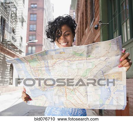 Stock Image - Mixed race woman holding map on urban street. Fotosearch