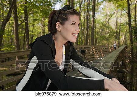 Stock Photo - Mixed race woman leaning on bridge railing. Fotosearch