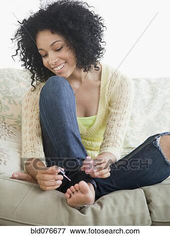 Stock Photo - Mixed race woman painting toenails. Fotosearch