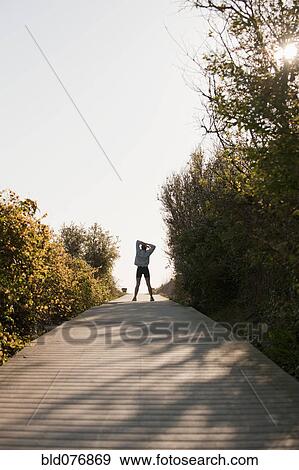 Stock Photo - Mixed race woman stretching on boardwalk. Fotosearch
