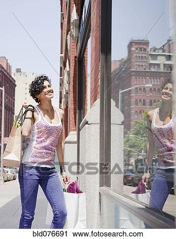 Mixed race woman window shopping on urban street View Large Photo Image Stock Image - Mixed race woman window shopping on urban street. Fotosearch