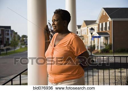 Pensive African woman standing on front stoop of house View Large Photo Image Stock Photograph - Pensive African woman standing on front stoop of house. Fotosearch