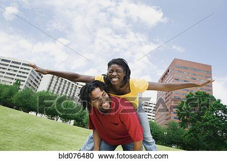 Stock Image - Playful couple in urban park. Fotosearch