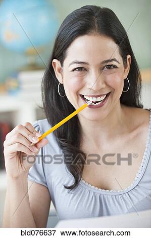 Smiling Hispanic woman biting pencil eraser View Large Photo Image Stock Photo - Smiling Hispanic woman biting pencil eraser. Fotosearch