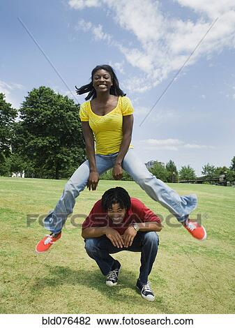 Woman leaping over man in park View Large Photo Image Stock Image - Woman leaping over man in park. Fotosearch