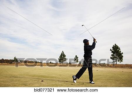Stock Image - African boy swinging golf club. Fotosearch