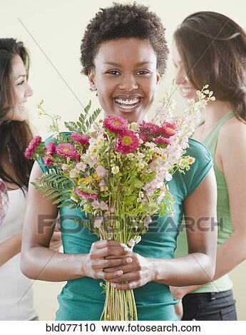 Stock Image - African woman holding bouquet of flowers. Fotosearch