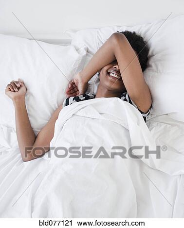 Stock Image - African woman laying in bed. Fotosearch
