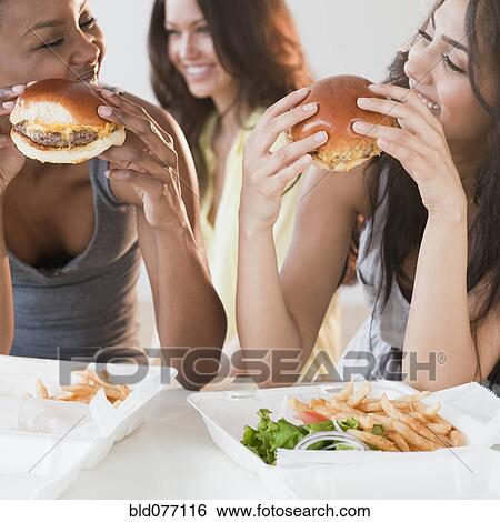 Stock Photograph - Friends eating take-out hamburgers and french fries. Fotosearch