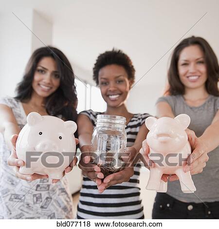 Stock Photo - Friends holding out glass jar and piggy banks. Fotosearch