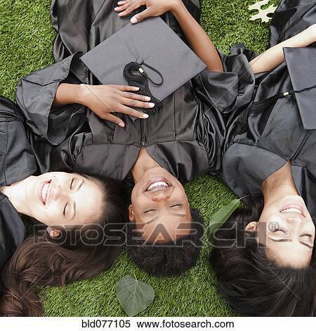 Friends in caps and gowns laying in grass View Large Photo Image Stock Photography - Friends in caps and gowns laying in grass. Fotosearch