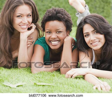 Stock Photograph - Friends laying and relaxing in grass. Fotosearch