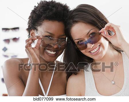 Stock Photo - Friends shopping for sunglasses. Fotosearch