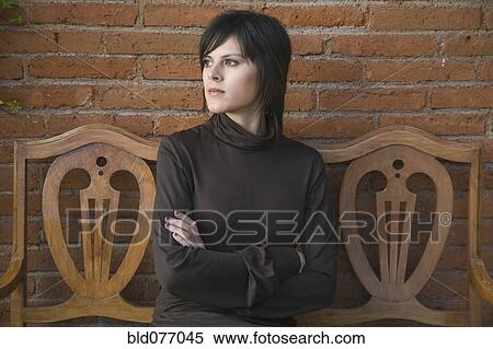 Stock Photography - Frustrated Hispanic woman sitting on bench. Fotosearch