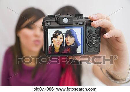 Stock Photograph - Hispanic friends taking self-portrait with digital camera. Fotosearch