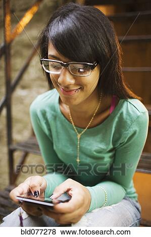 Hispanic girl text messaging on staircase View Large Photo Image Stock Photo - Hispanic girl text messaging on staircase. Fotosearch
