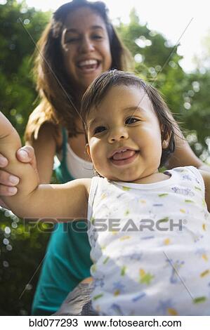 Stock Image - Hispanic mother helping baby boy to walk. Fotosearch