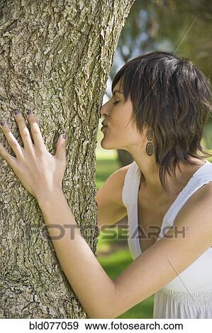 Stock Photo - Hispanic woman hugging tree trunk. Fotosearch