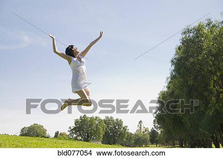 Picture - Hispanic woman jumping in mid-air. Fotosearch