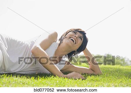 Stock Image - Hispanic woman laying in grass. Fotosearch