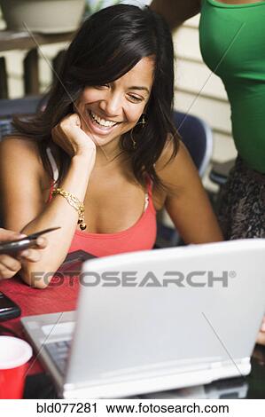Stock Image - Hispanic woman smiling at laptop. Fotosearch