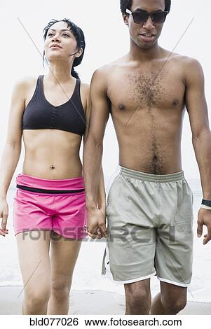 Stock Photograph - Mixed race man jumping in air on beach. Fotosearch