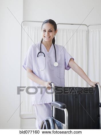Stock Image - Mixed race nurse pushing wheelchair. Fotosearch