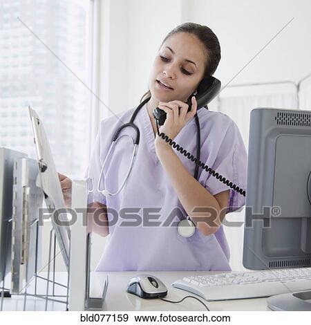 Mixed race nurse talking on telephone in hospital View Large Photo Image Stock Photo - Mixed race nurse talking on telephone in hospital. Fotosearch