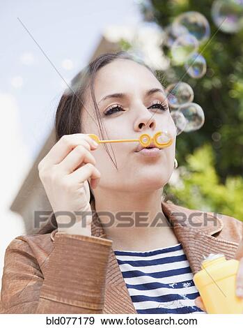 Stock Photo - Mixed race woman blowing bubbles. Fotosearch