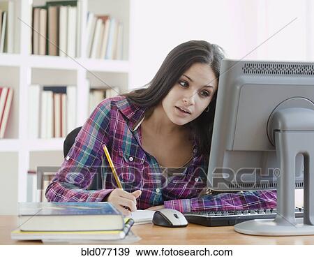 Stock Photo - Mixed race woman doing homework at computer. Fotosearch