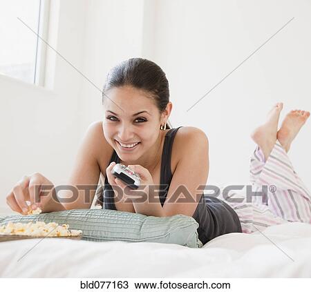 Mixed race woman eating popcorn and watching television View Large Photo Image Stock Image - Mixed race woman eating popcorn and watching television. Fotosearch