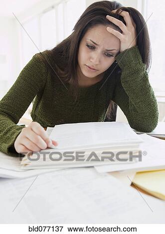 Stock Photo - Mixed race woman frustrated over paperwork. Fotosearch