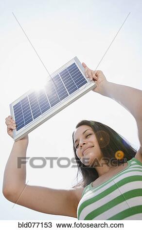 Stock Image - Mixed race woman holding solar panel. Fotosearch