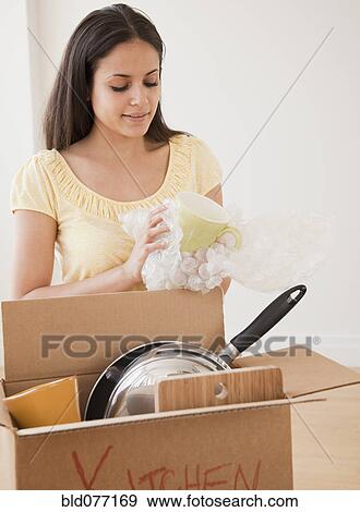 Stock Photo - Mixed race woman packing moving box. Fotosearch